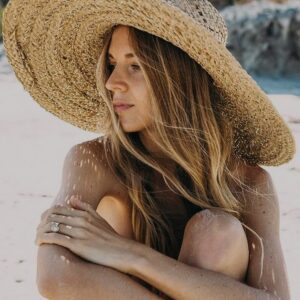 Kvinde på stranden med stor hat
