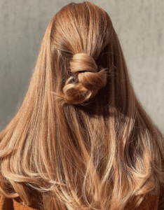 Kvinde med langt hår, hvor halvdelen af håret er sat op i en knold. Der er en flot rødlig toning i håret.